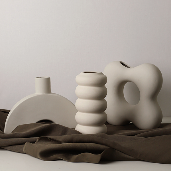 Three unique ceramic vases on a textured surface with a neutral background