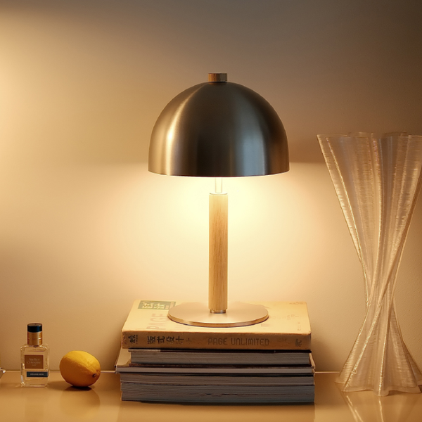 Table lamp with a black dome shade on a stack of books, illuminated in a warm room setting.