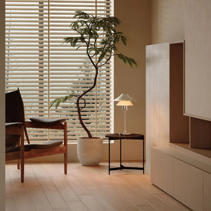 Modern interior design with a plant, chair, and table in a room with neutral tones.
