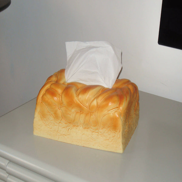 Tissue box shaped like a loaf of bread on a surface with a white background