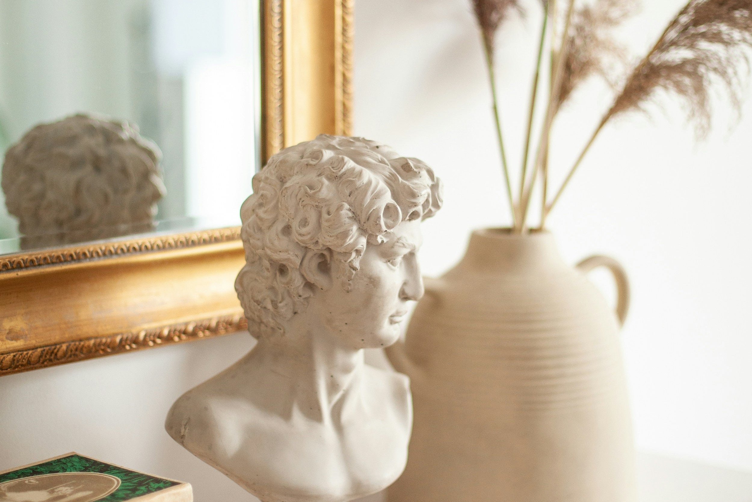 Decorative setup with a bust, vase, and books on a shelf.